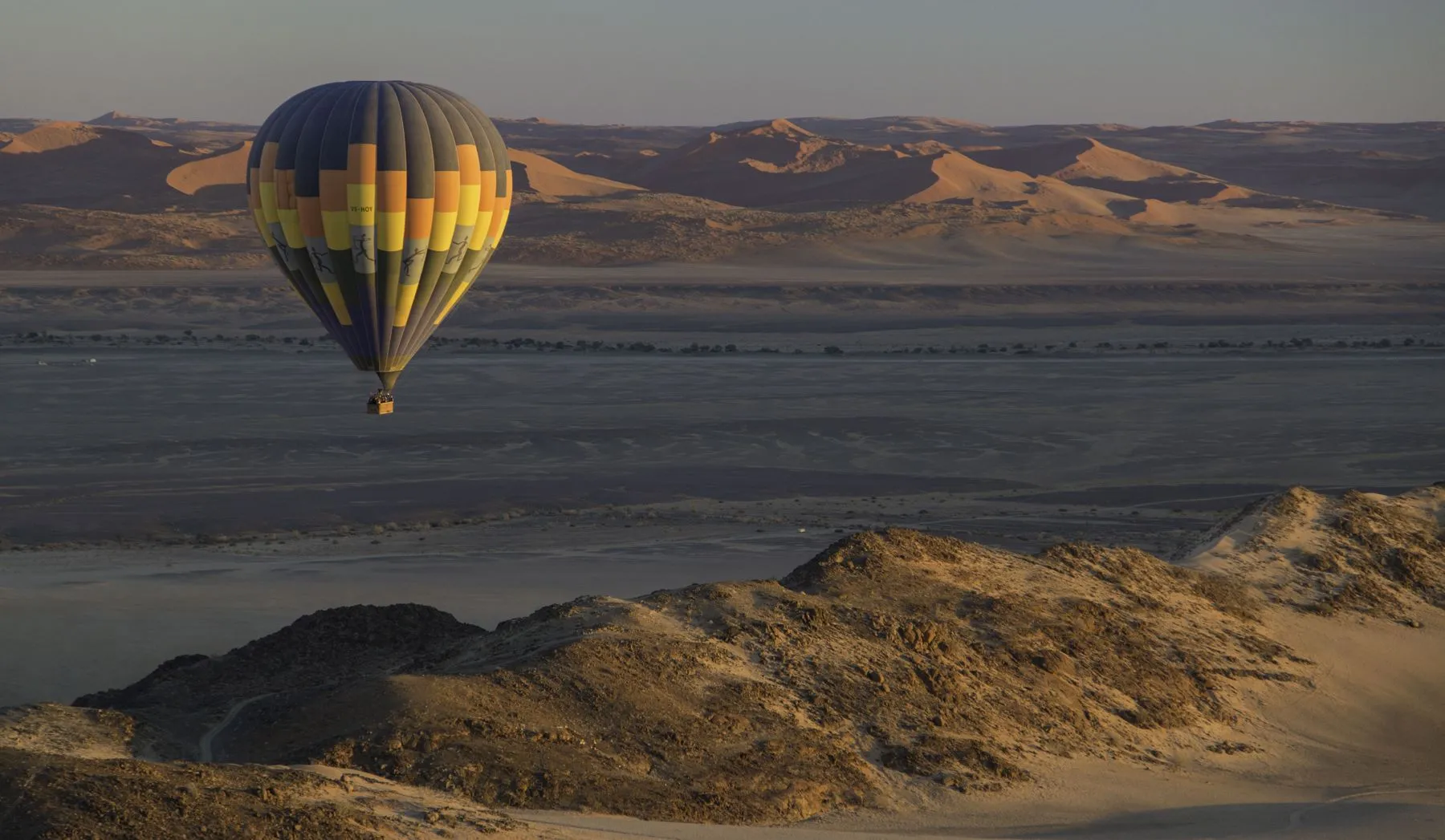 A hot air balloon drifting over the Namib dunes at dawn