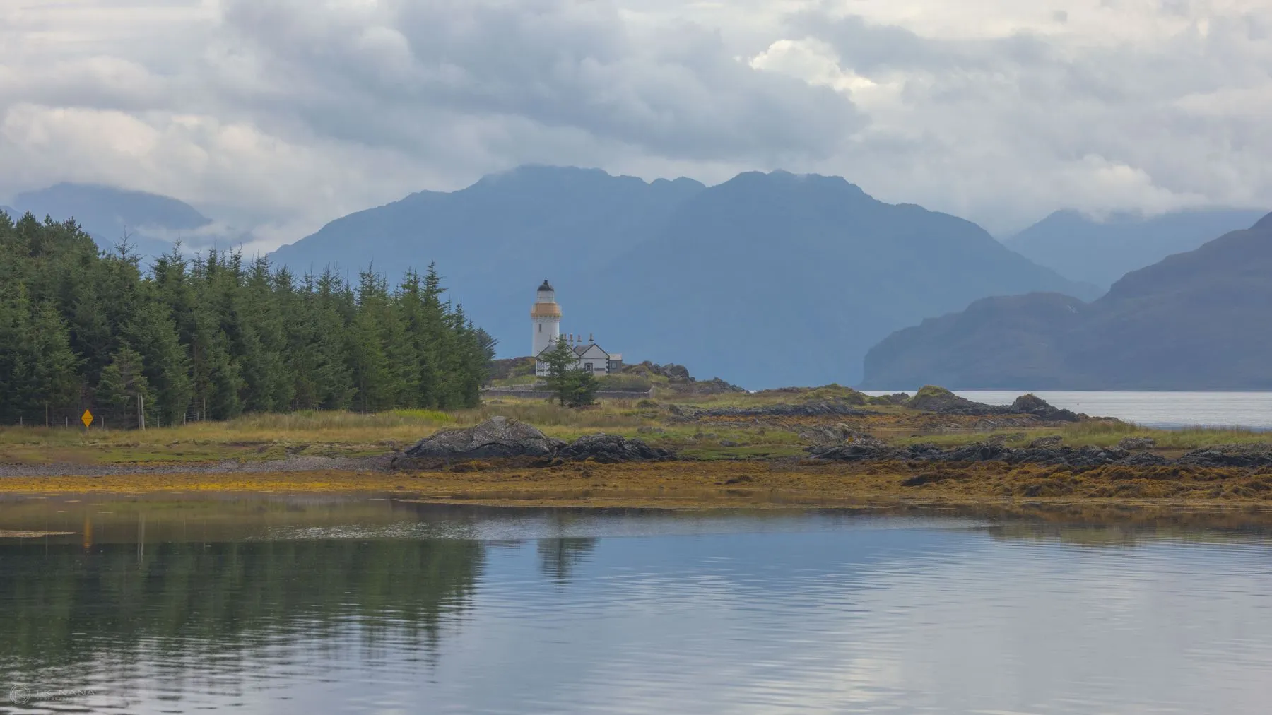 A small lighthouse on a still loch below the mountains of Skye