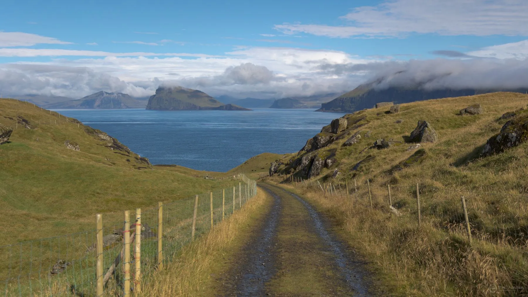 A grass track running down to the sea between hills in the Faroe Islands