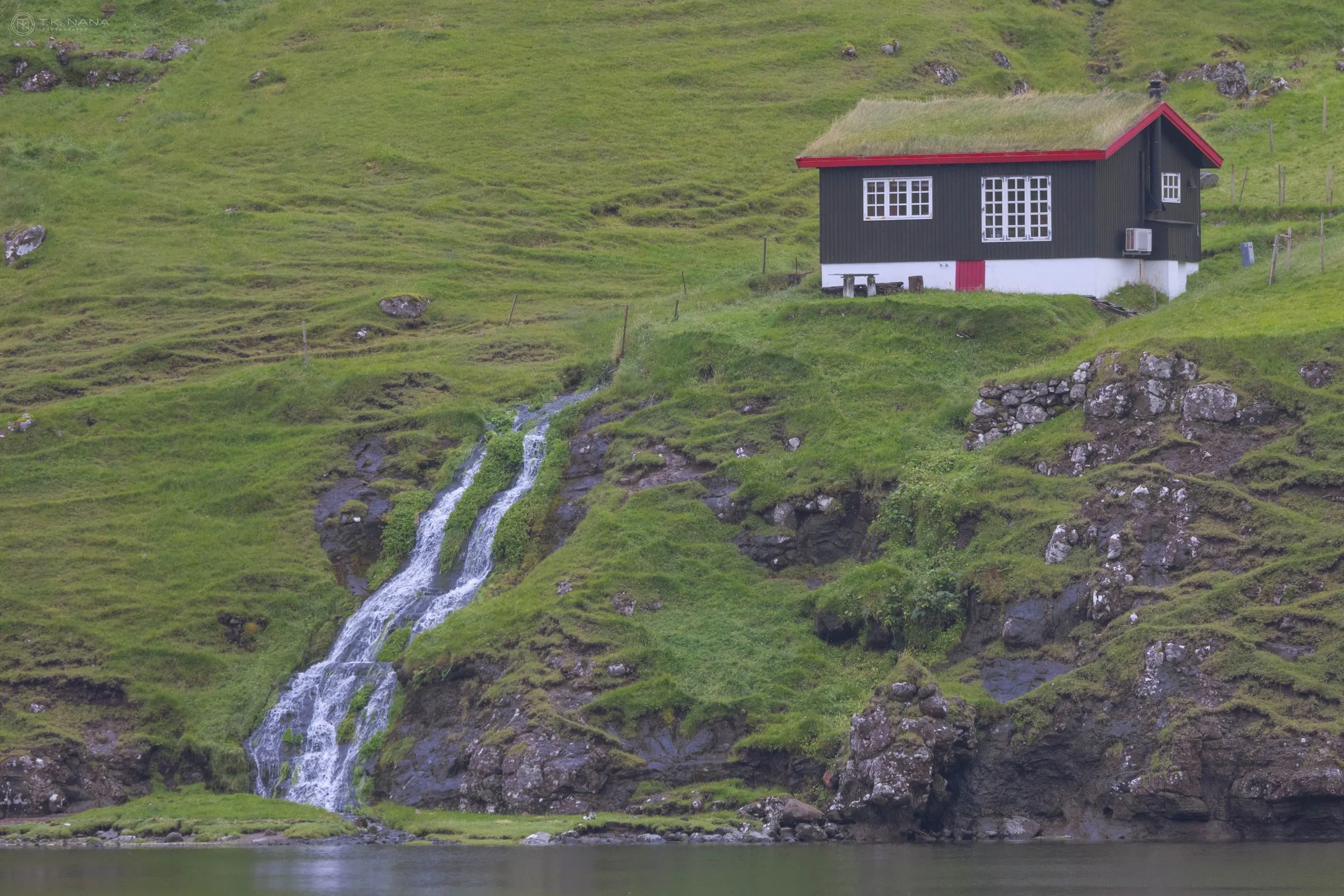 A turf-roofed house above a stream running to the sea